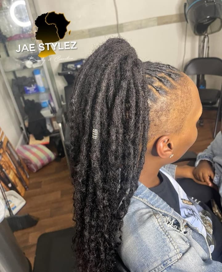 Long locs styled in a high ponytail with a loc jewelry accent